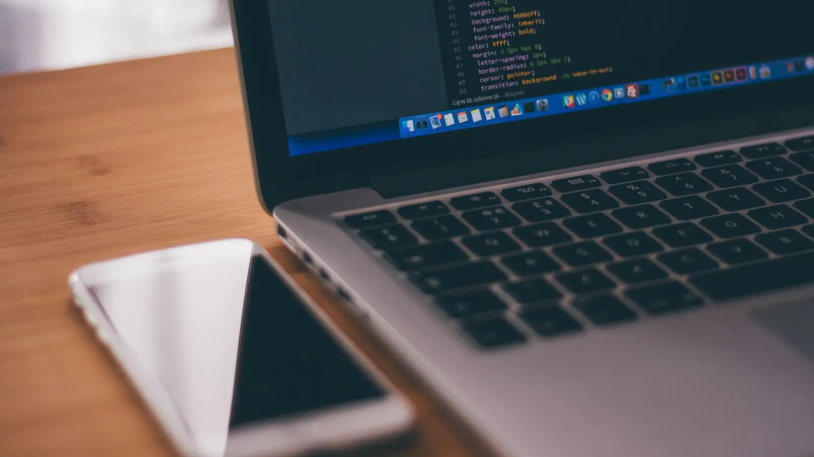 An Android smartphone beside a laptop showing code