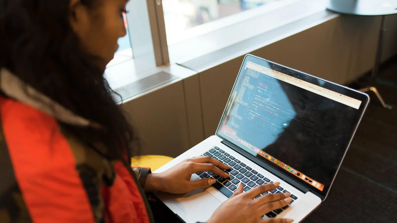 A developer writing code on a laptop at a café table