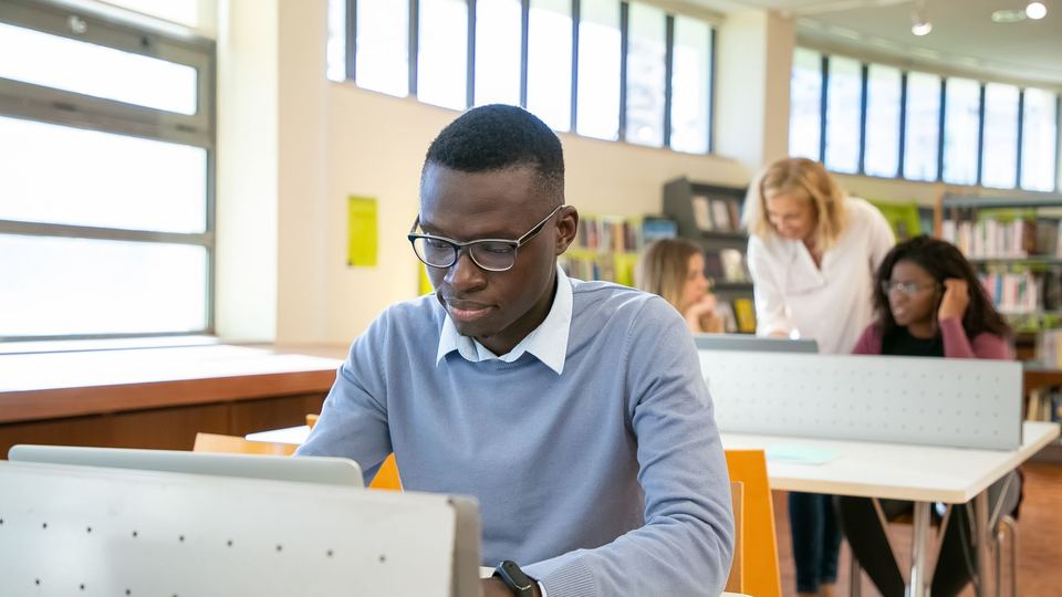 A student learning on a laptop in a library